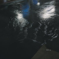 雨で滑りやすそうな夜間の歩道、雨天時の危険な路面状況の写真