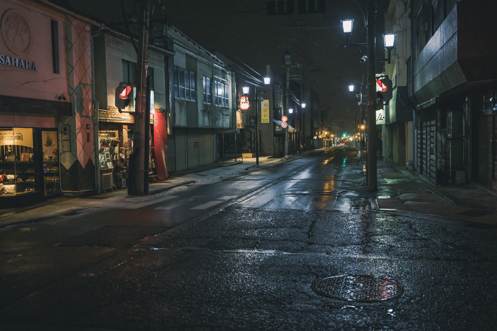 夜間の雨で濡れた交差点と街灯、ネオン看板が映る景色