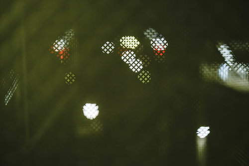 金網越しに見える夜景の灯り、防柵背景の街灯照明