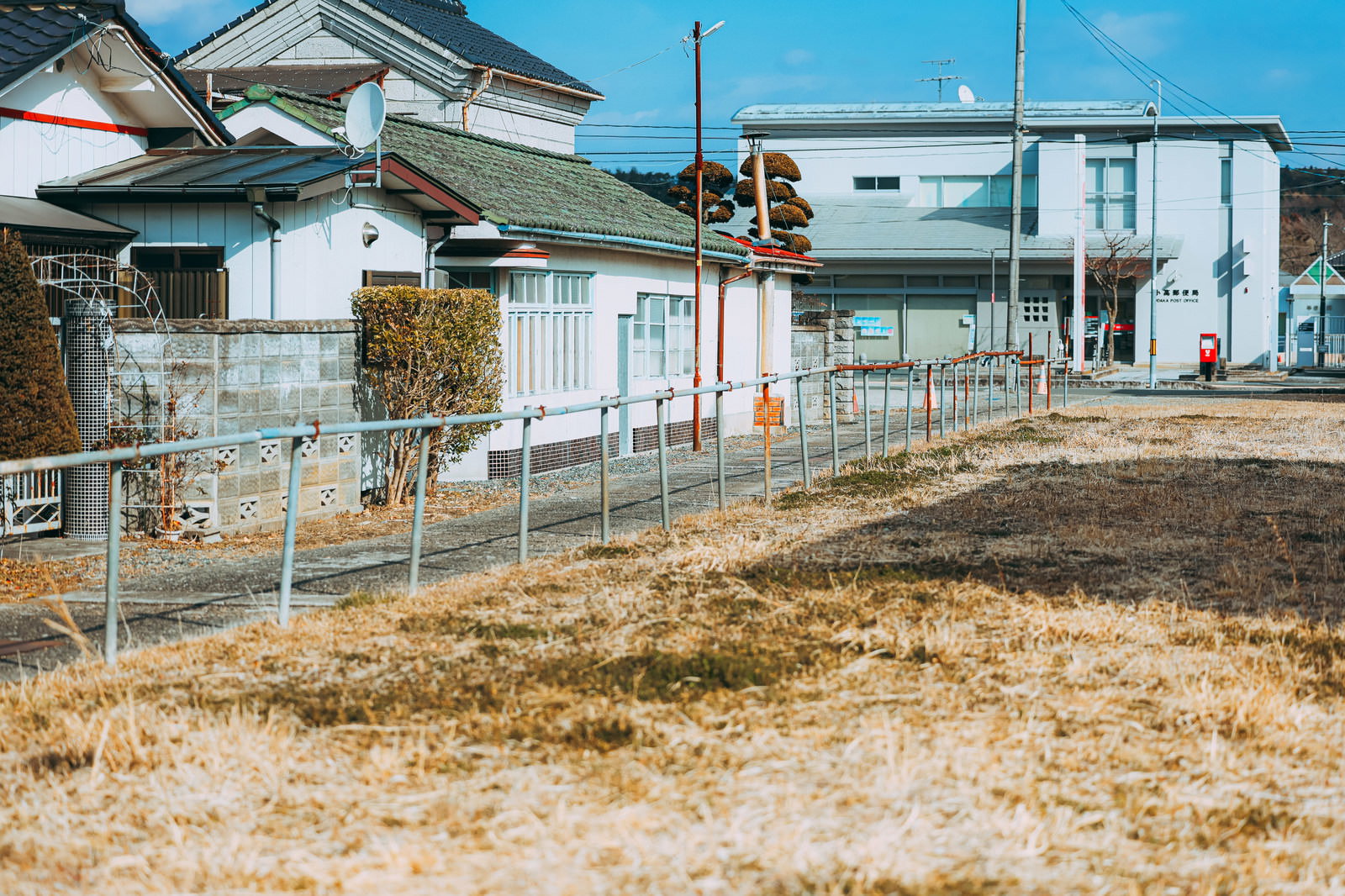福島県小高地区の住宅街と空き地、晴天下で白い民家が立ち並ぶ風景