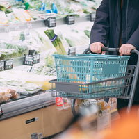 買い物カートを押して青菜などの食材を選ぶ様子の写真