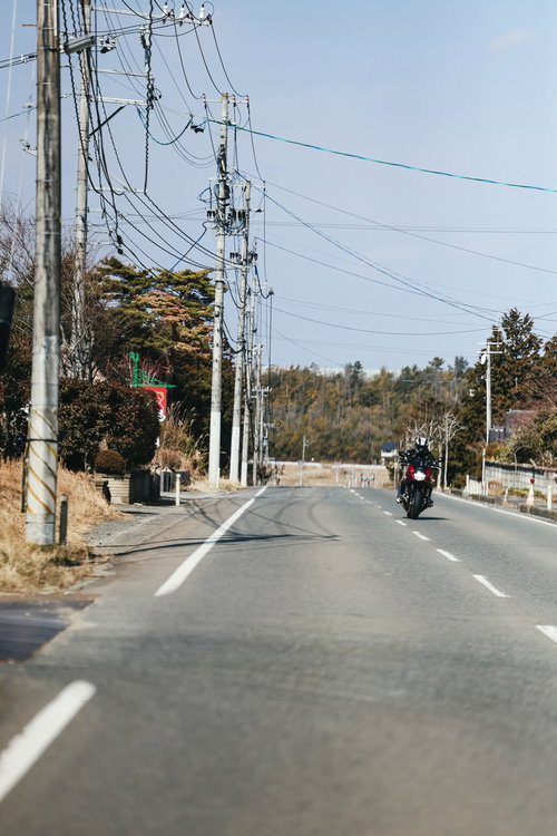 福島県の中通りを走行するバイクと電柱が立ち並ぶ道路