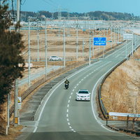 南相馬に向かう道路を走る白い乗用車とバイクの写真