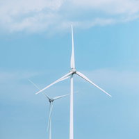 南相馬の海岸沿いに立つ白い風力発電タービンの写真