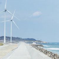 南相馬の海岸沿いに立つ風力発電の白い大型風車の写真
