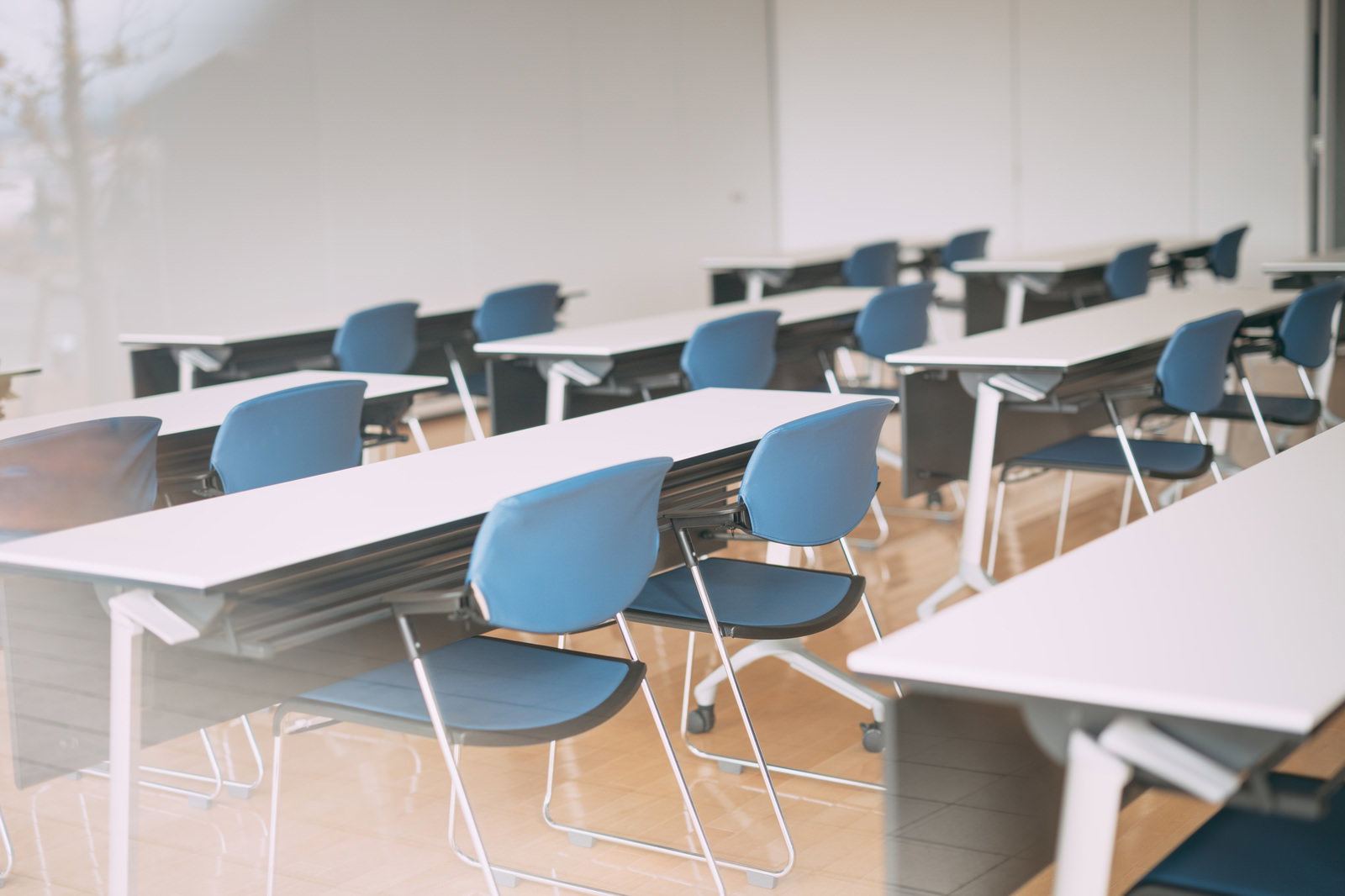 白いテーブルと青いチェアが複数配置された会議室の内部