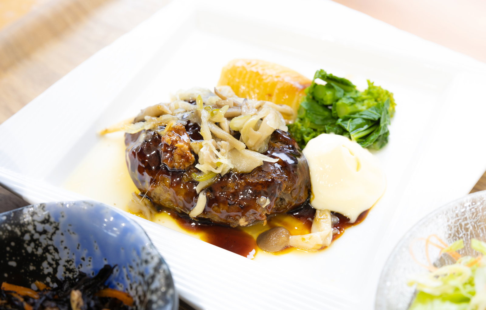 白い皿に盛られたきのこハンバーグとコーン、ブロッコリーのセット