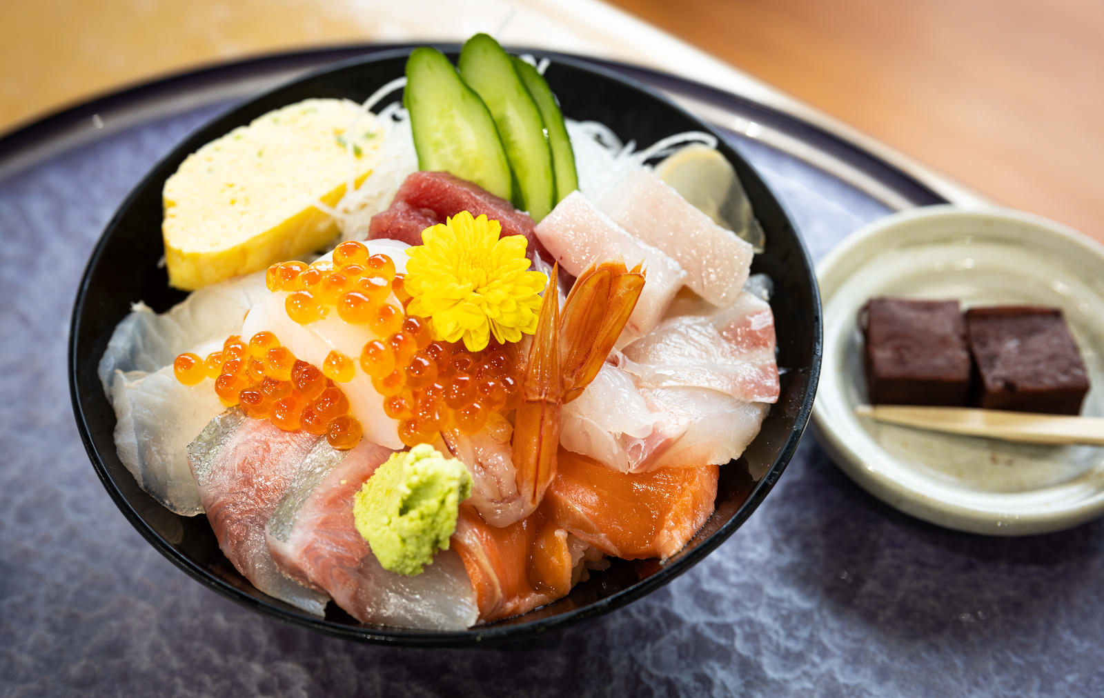 黒い皿に盛られたいくらと刺し身の海鮮丼