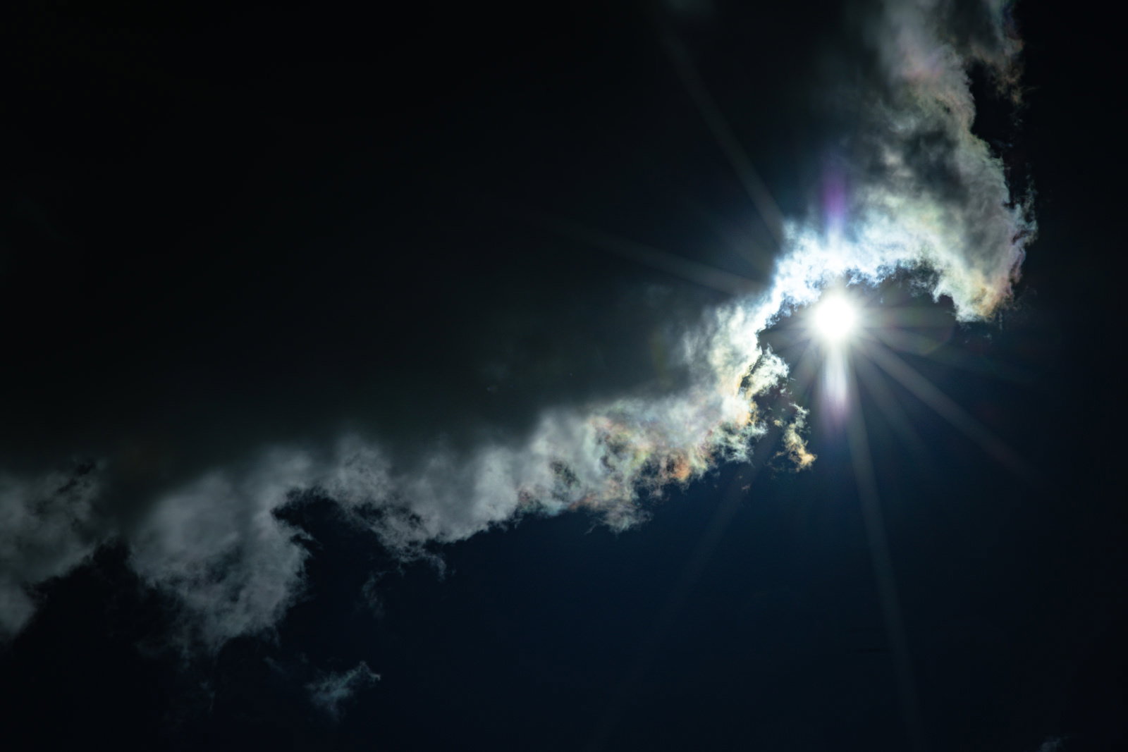 彩雲と太陽が放つ光芒で包まれた曇りの空