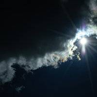 彩雲と太陽の光芒、雨雲に囲まれた空に広がる虹色の光景の写真