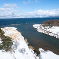 雪が積もる舟津公園から見た猪苗代湖と遠方の山々（空撮）の写真
