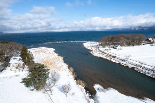 雪が積もる舟津公園から見た猪苗代湖と遠方の山々（空撮）