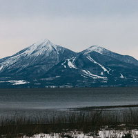 雪が残る2月上旬の磐梯山と猪苗代湖の湖畔の写真