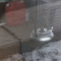小屋に置かれた灯油タンクと金属製やかん、冬の暖房用品の写真