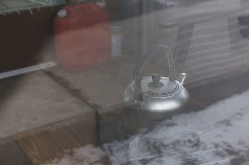 小屋に置かれた灯油タンクと金属製やかん、冬の暖房用品