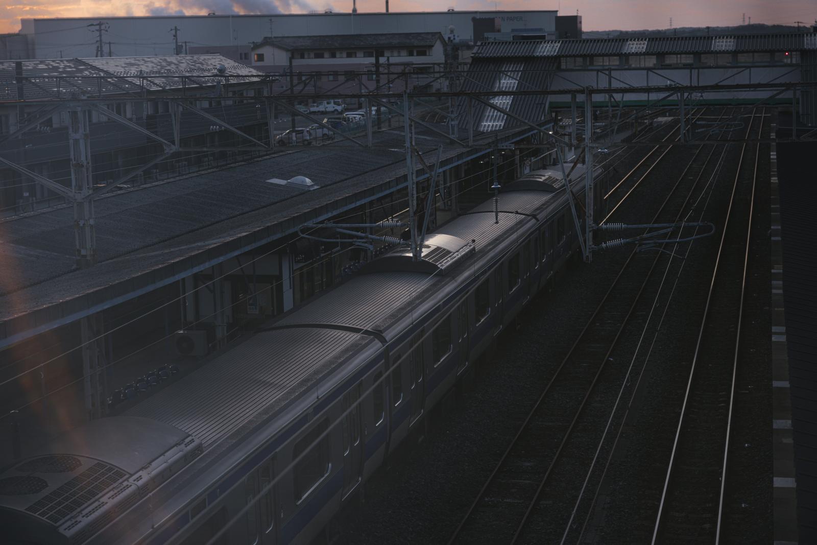 夕焼けに染まる空の下、原ノ町駅のホームに停車する電車を俯瞰で撮影した風景