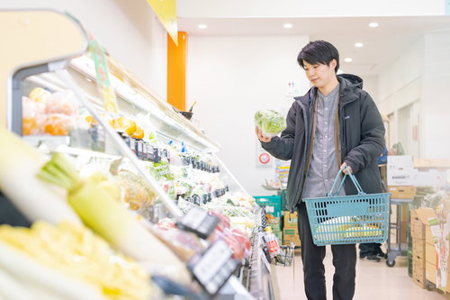 小高ストアの野菜コーナーで食材を選ぶ男性