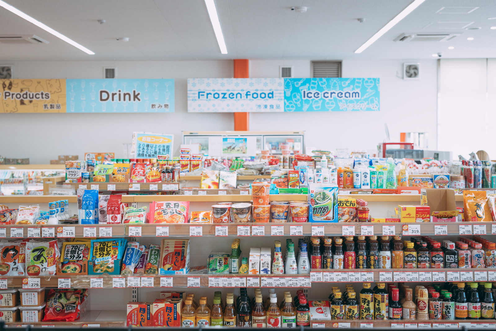 小高ストアの商品棚に並ぶドリンク、冷凍食品、アイスクリーム、インスタント食品などの商品