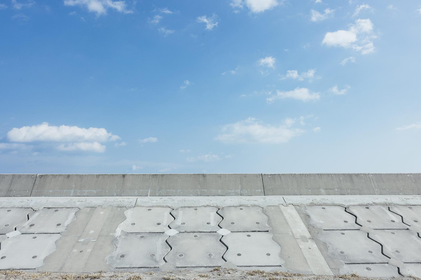 南相馬の海岸に連なる白いコンクリート製防波堤と青空