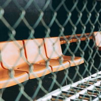 みちのく鹿島球場のオレンジベンチと金網フェンスの写真