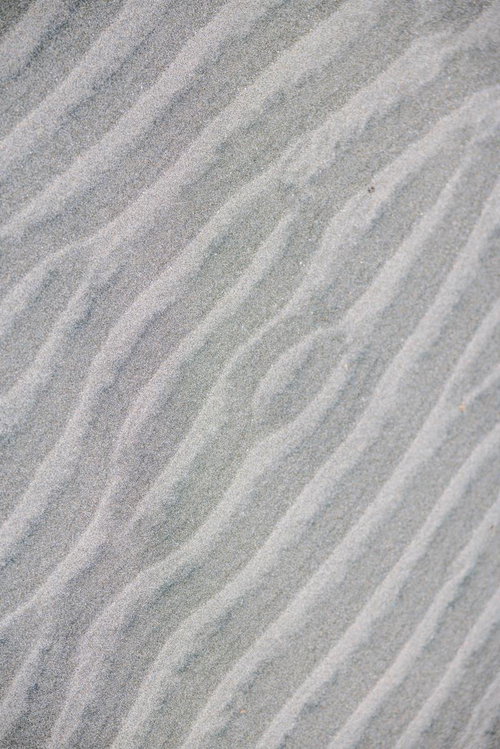 砂浜に刻まれた波跡の模様と光と影のテクスチャー