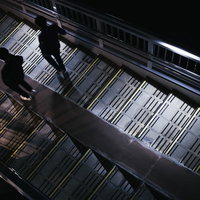 暗い歩道橋を降りる二人の姿：駅前の夜間風景の写真