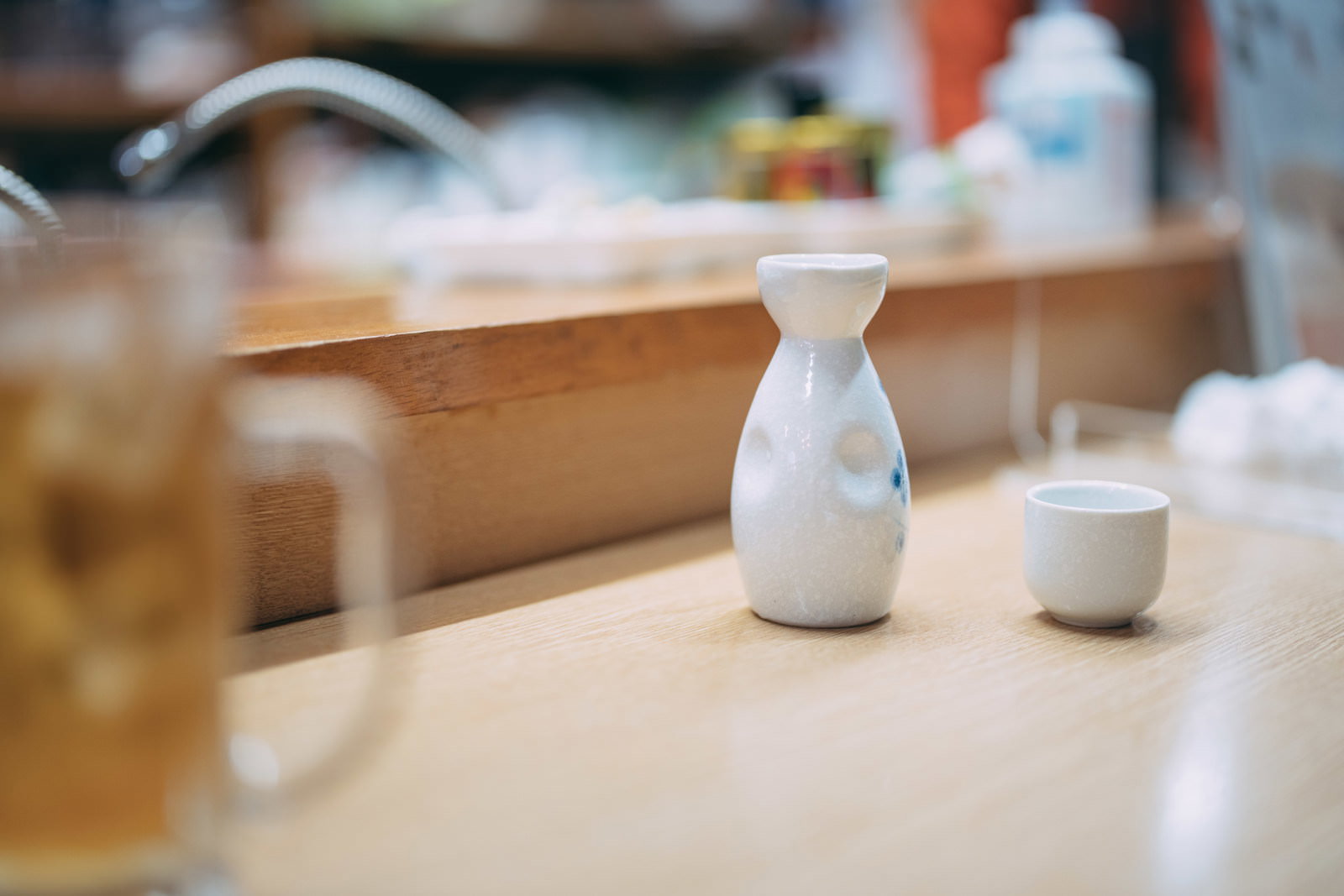 木製カウンターに置かれた白いとっくりと盃で熱燗を飲む