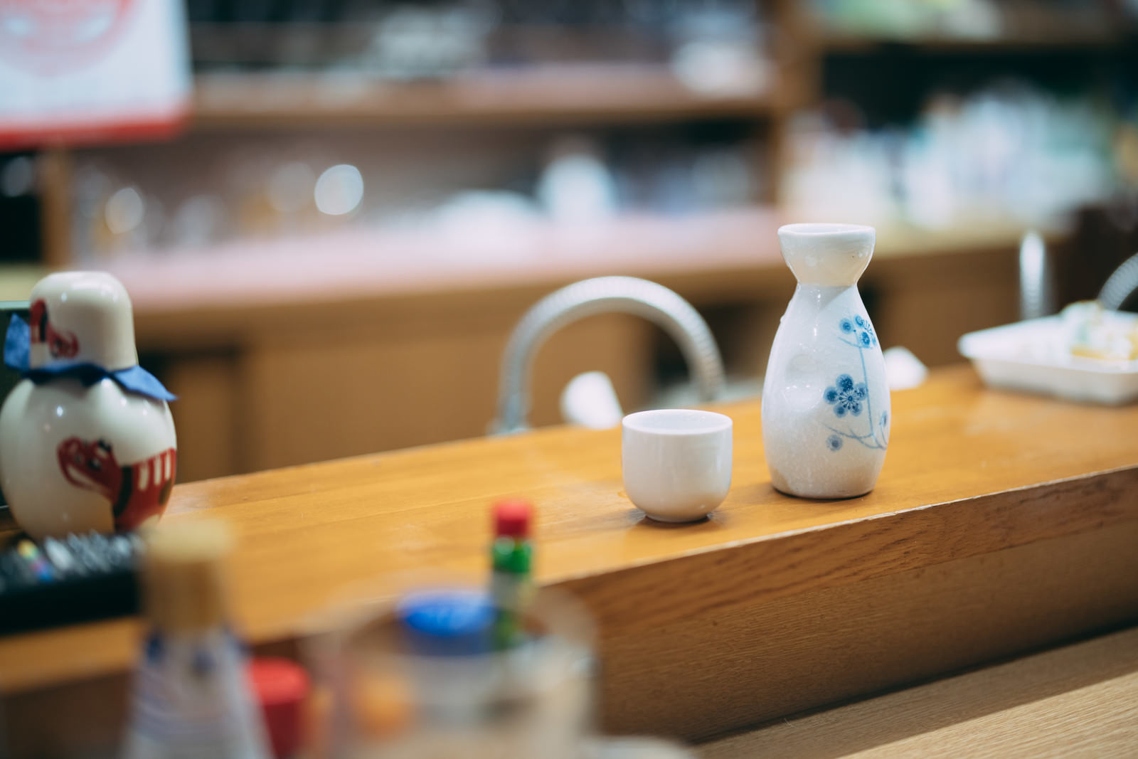 木製テーブルの上に置かれた白い徳利とおちょこ、日本酒の熱燗