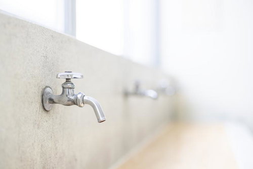 廃校舎に残る学校の水飲み場の蛇口と経年劣化したコンクリート壁