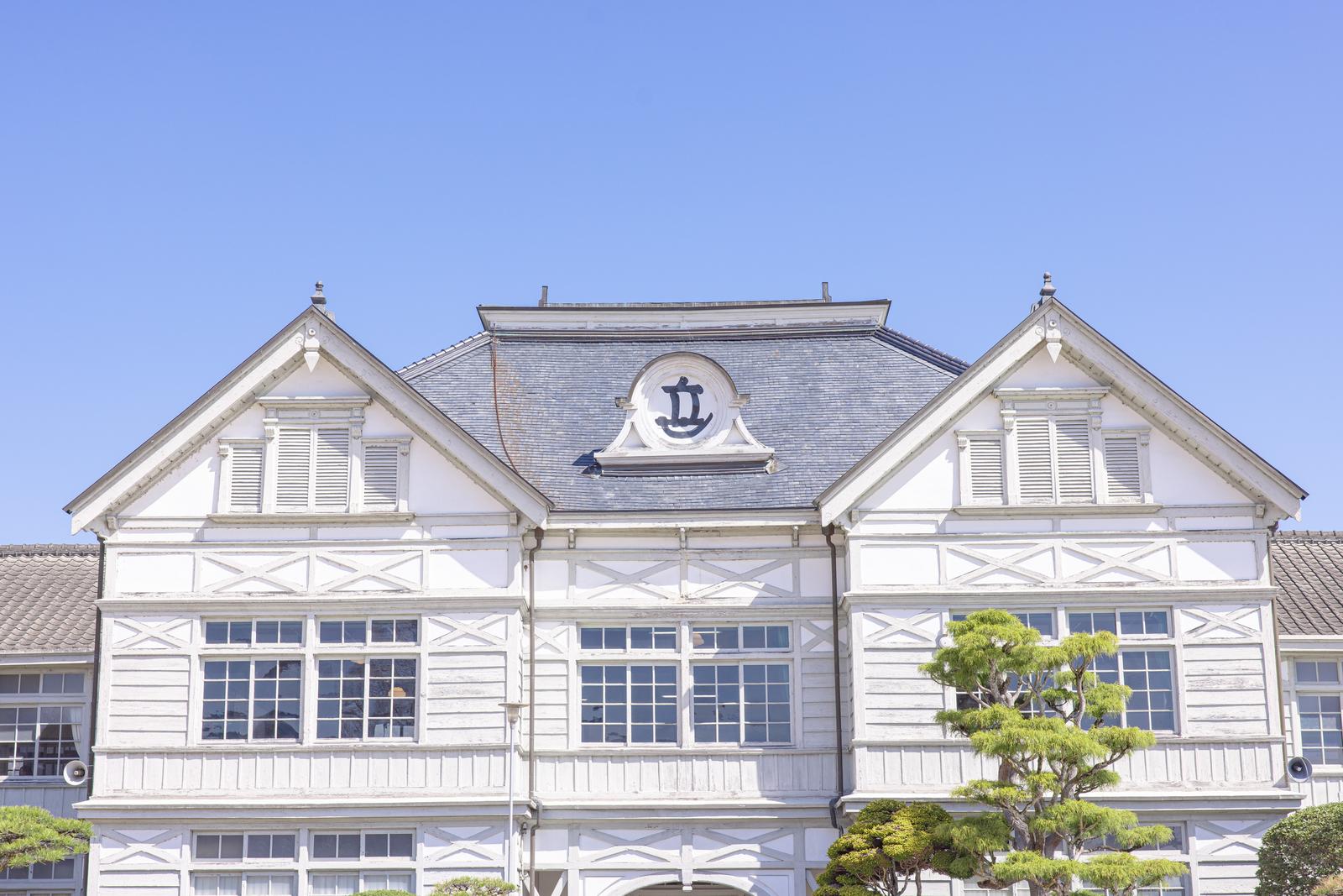 白い壁と青いスレート屋根のルネッサンス様式の旧遷喬尋常小学校木造校舎