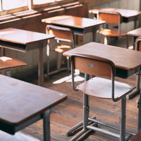木製の学習机と椅子が整然と並ぶ旧遷喬尋常小学校の教室の写真