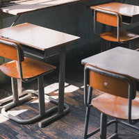 放課後の学習机と椅子が並ぶ旧遷喬尋常小学校の教室の写真