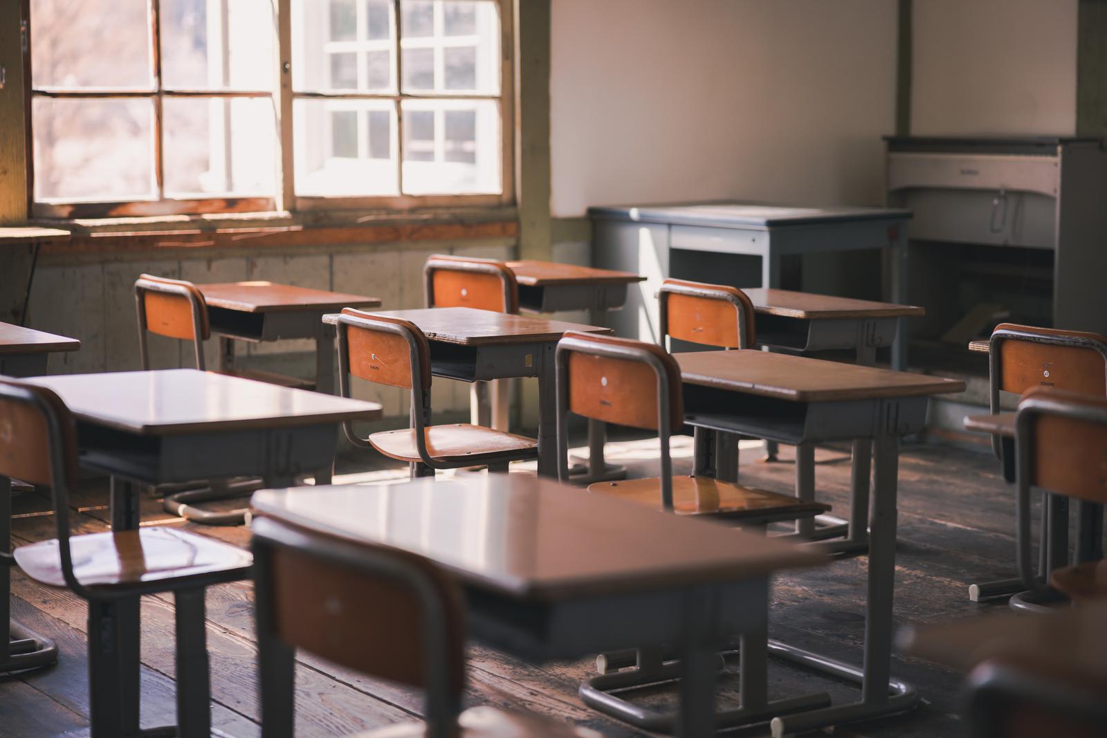 放課後の教室に並ぶ茶色い木製の学習椅子と机