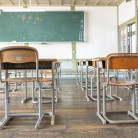 教育の基盤、学習机と椅子が並ぶ旧遷喬尋常小学校の教室の写真