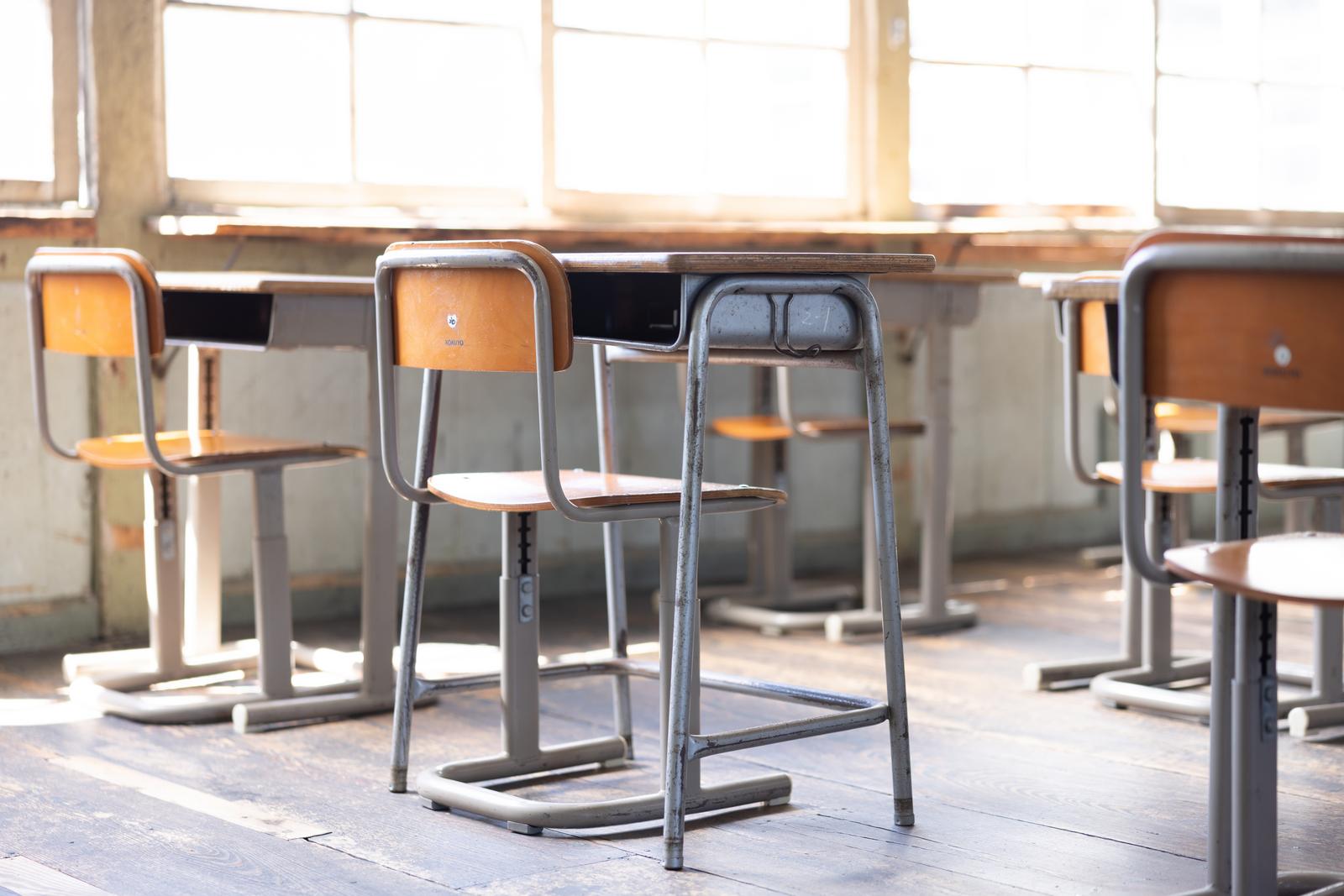 オレンジ色の座面の学習椅子と机が配置された明るい教室