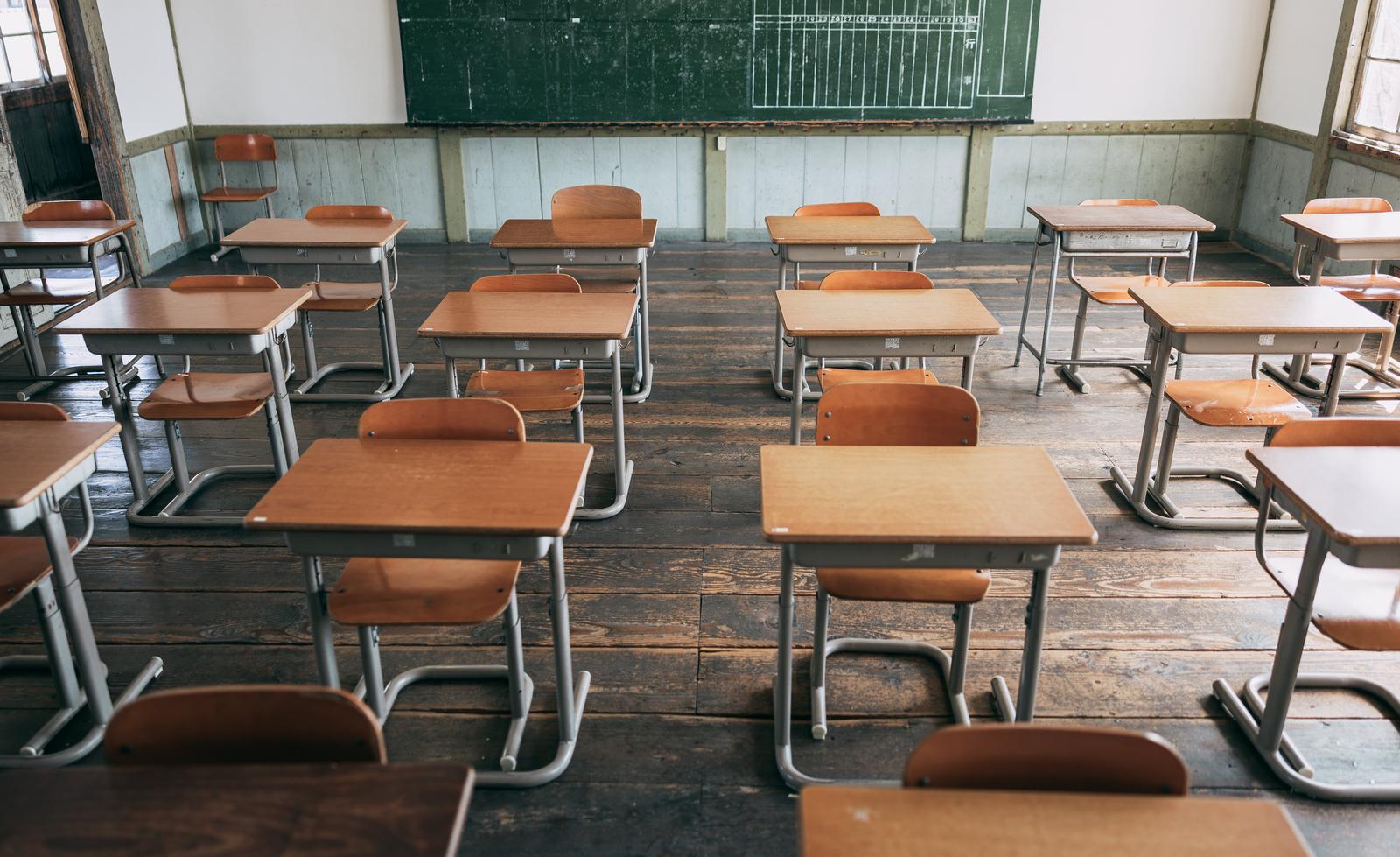 旧遷喬尋常小学校の教室内に並ぶ赤茶色の椅子と木製の学習机