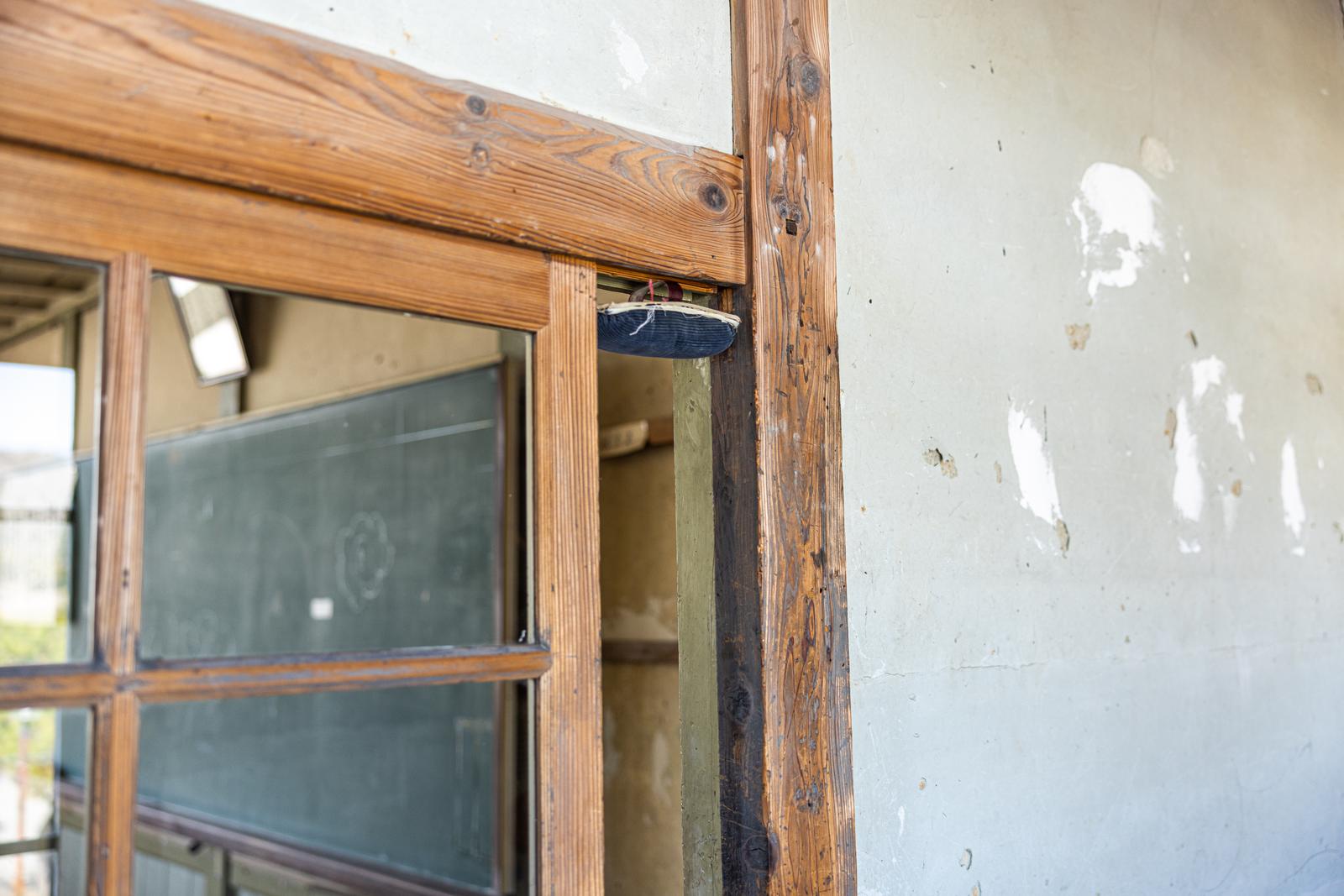 古い木製の校舎の扉上に紐で引っかけられた紺色の黒板消し