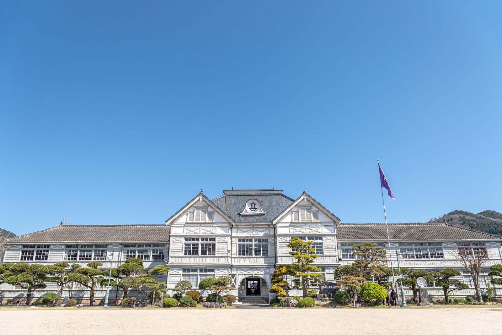 白い壁と灰色瓦屋根のルネッサンス様式の木造校舎。岡山県の旧遷喬尋常小学校