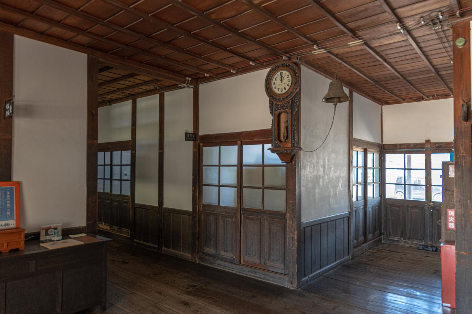 木造校舎の廊下に設置された懐かしい木製の柱時計と格子窓