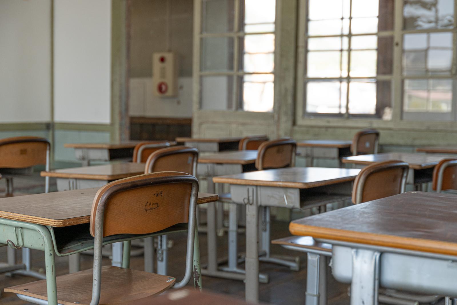 旧遷喬尋常小学校の教室内に並んだ木製の学習机と椅子