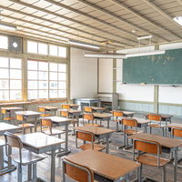 窓から差し込む自然光が満ちる旧遷喬尋常小学校の教室風景の写真