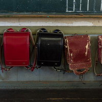 使い込まれたランドセルが並ぶ校舎の壁｜旧遷喬尋常小学校の写真