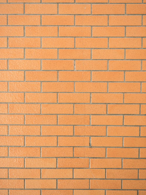 一色のオレンジ色レンガ調タイル壁のテクスチャ