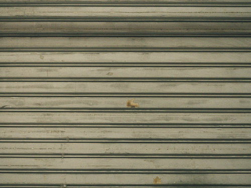 金属製シャッターの擦れた跡と風化したテクスチャー