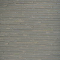 グレー系の小さなタイルが規則正しく並ぶ建物の外壁の写真