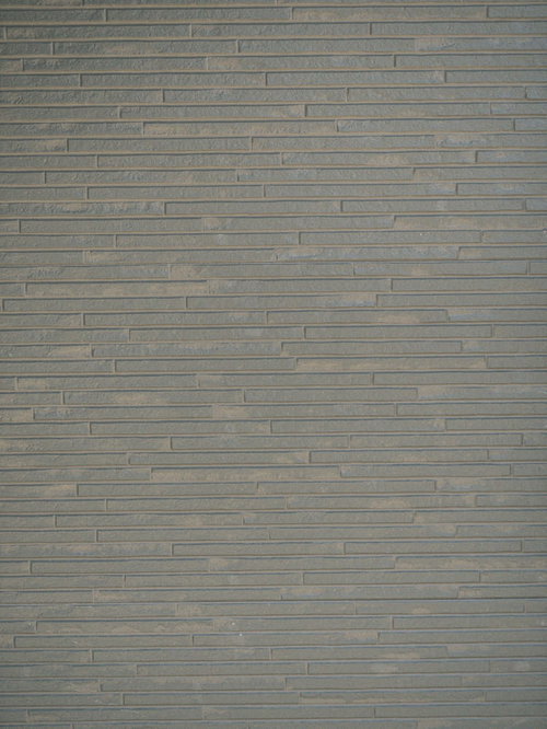 グレー系の小さなタイルが規則正しく並ぶ建物の外壁