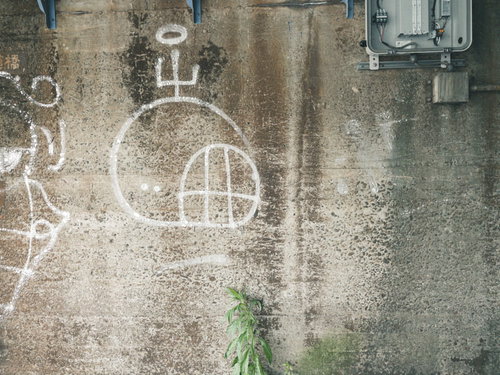 白い落書きが描かれたコンクリート擁壁のテクスチャ