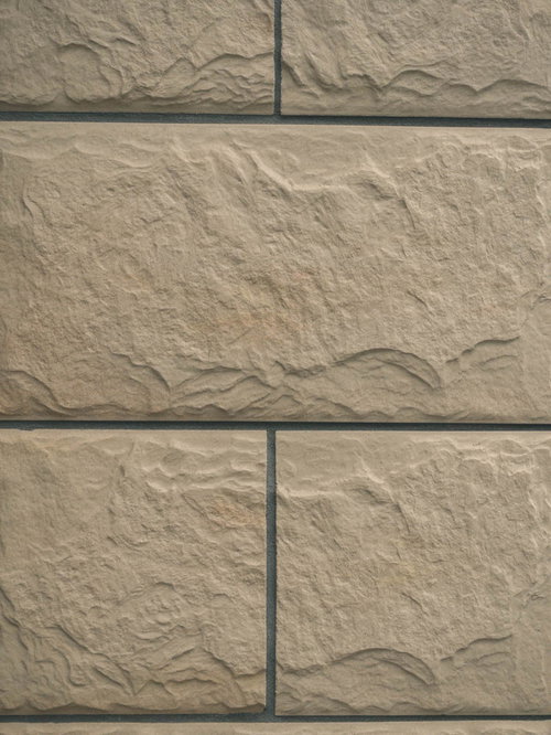 幅広い横長のベージュタイルが規則正しく並ぶ壁