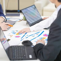 会議室でパソコンと資料を使ったビジネスマンの打ち合わせの写真