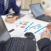 ノートパソコンと資料を前に進める社内の企画会議の写真